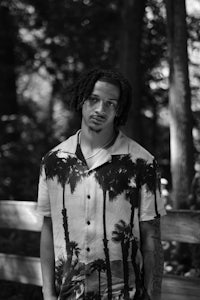 a black and white photo of a man with dreadlocks